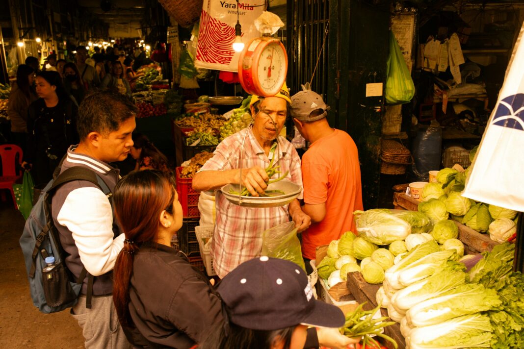 A bustling market in Baguio City with vendors and shoppers, showcasing fresh vegetables and vibrant atmosphere.