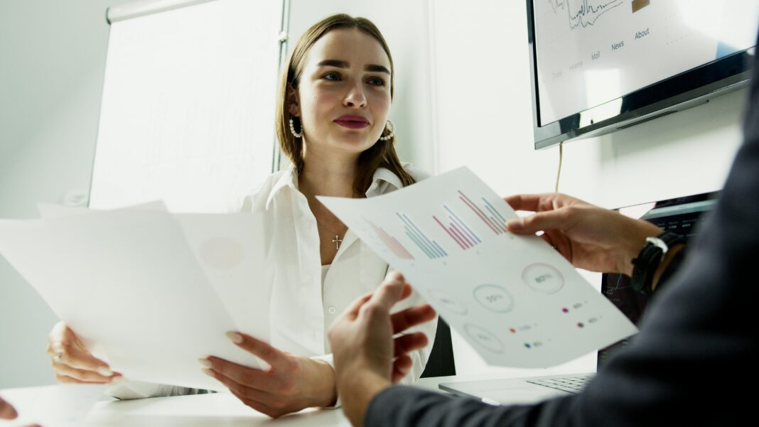 Business professionals sharing charts in a meeting room discussion.